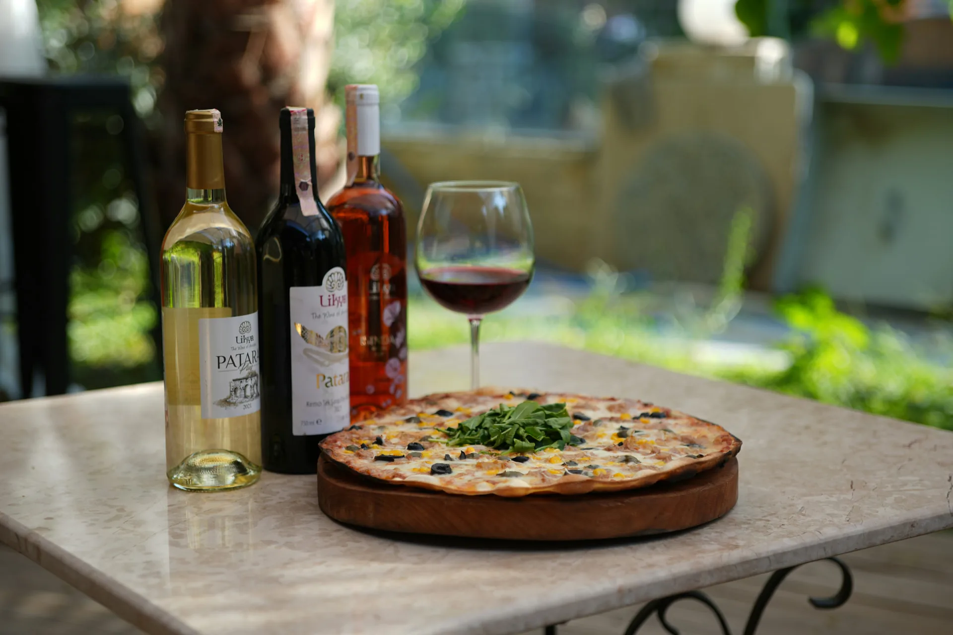Witte, rode en roséwijn met een glas rode wijn op een tuintafel