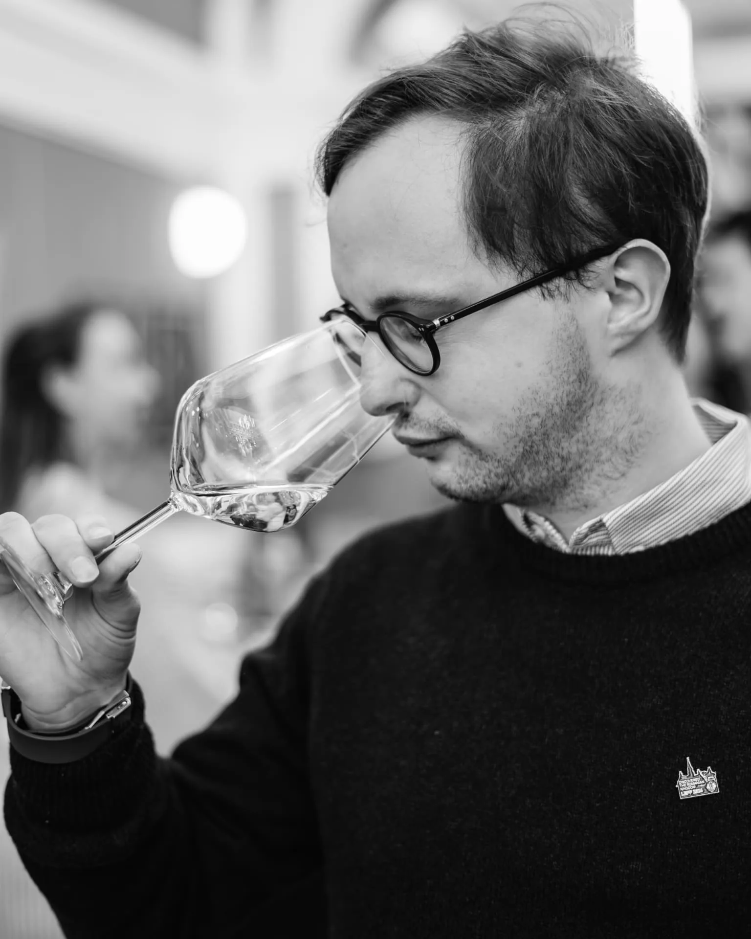 Alexandre ruikt aan een glas witte wijn tijdens een degustatie, in zwart-wit